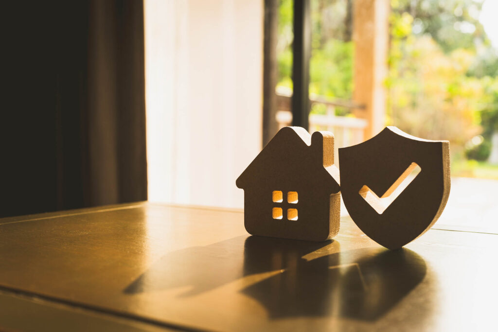 Wooden cut out of a house and a tick mark silhouetted by a window.