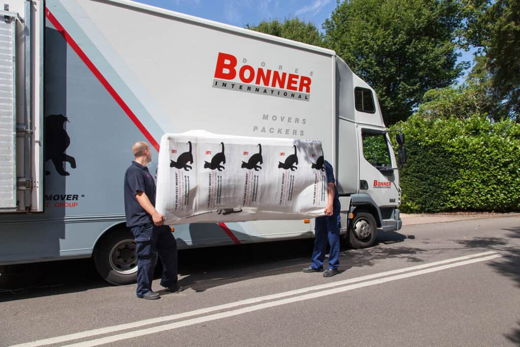 Doree Bonner removals truck with staff carrying furniture outside.